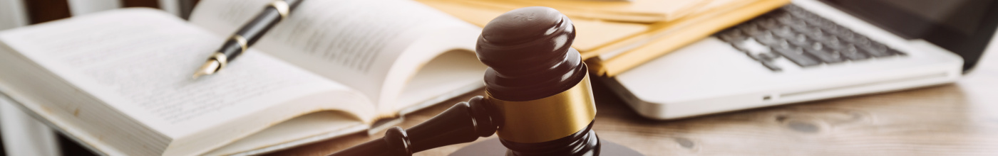 a photo of a table with a gavel in front of open books and a laptop