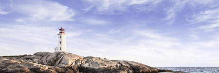 A landscape image of a lighthouse on a rocky point with blue skies